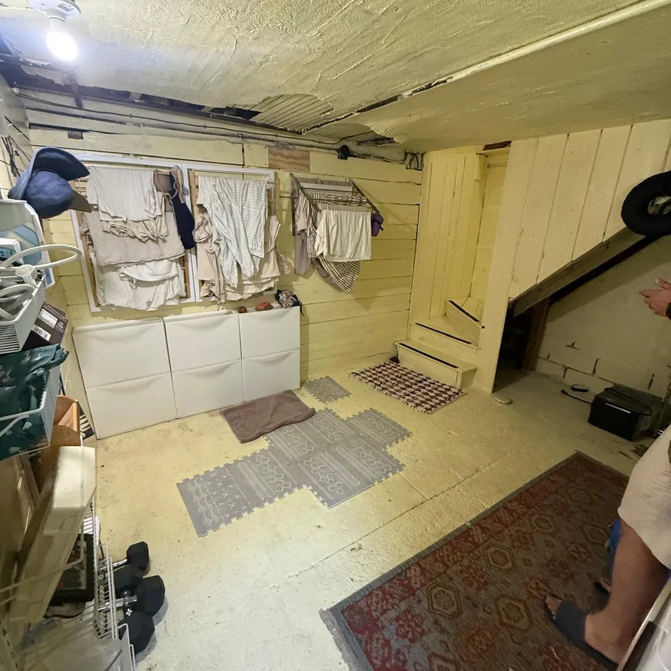 Before: unfinished laundry corner and old basement stairs in an Arlington, MA home