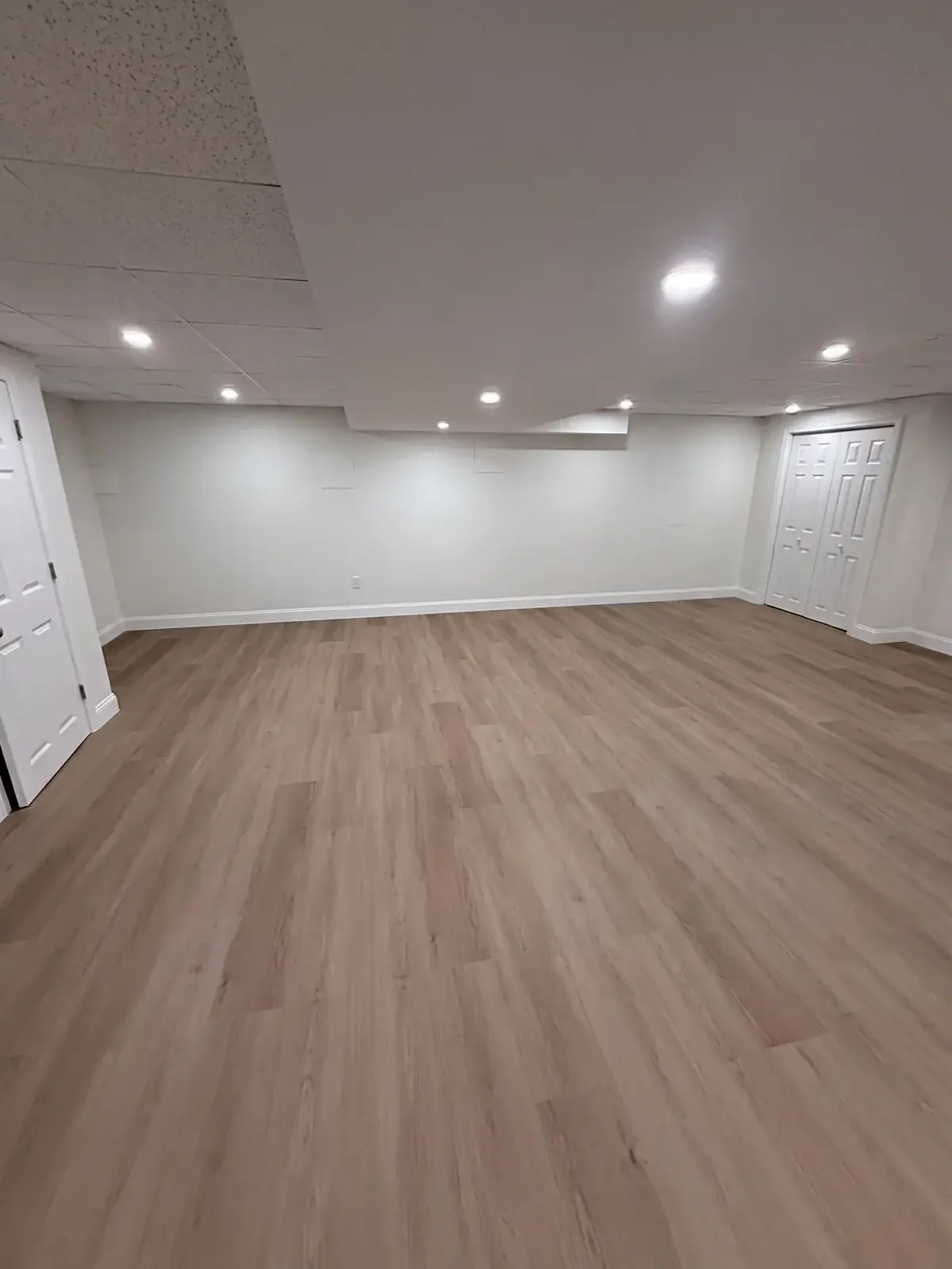 Finished basement with recessed lighting and new floors by Innov Builders