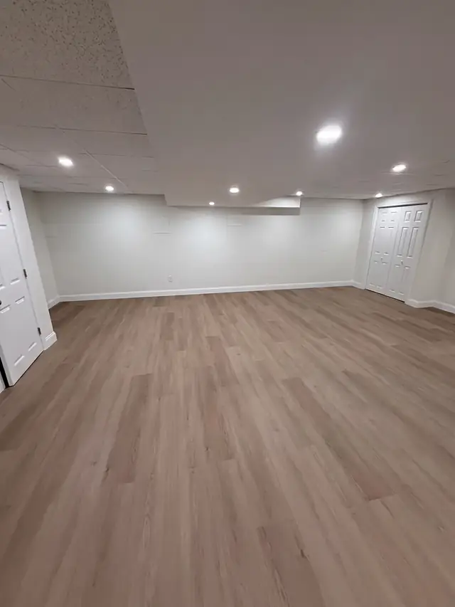 Open finished basement with recessed lights by Innov Builders