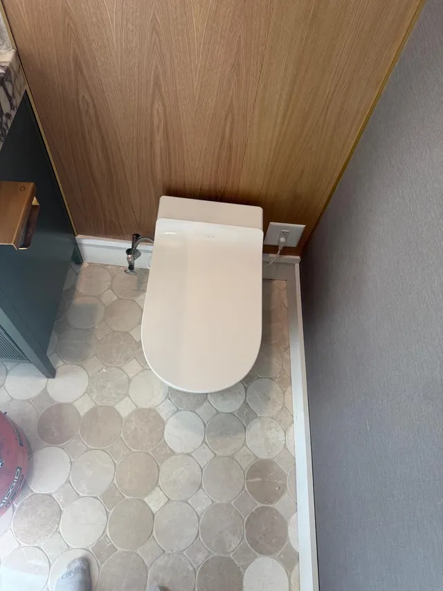 Basement half bath with wood-paneled wall and tile floor in Beverly, MA